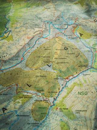 Ausschnitt einer topografischen Wanderkarte mit Höhenlinien, Flüssen, Hütten und Wegen in einem Gebirgsgebiet.