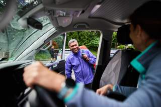 Lächelnder Mann steigt vorne in Auto ein