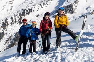 Zwei erwachsene Personen und zwei Kinder posieren in Skitourenausrüstung für ein Gruppenfoto