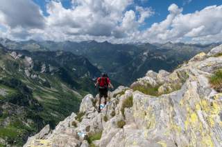 Ein Bergsteiger mit Wanderstöcken auf felsigem Untergrund.