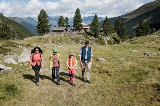 Familie bricht zum Wandern auf. Im Hintergrund die Hütte.