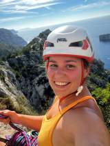 lächelnde Frau mit Helm, kletternd am Berg